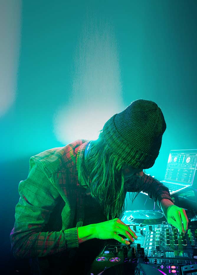 DJ in a hat turning nobs on his equipment