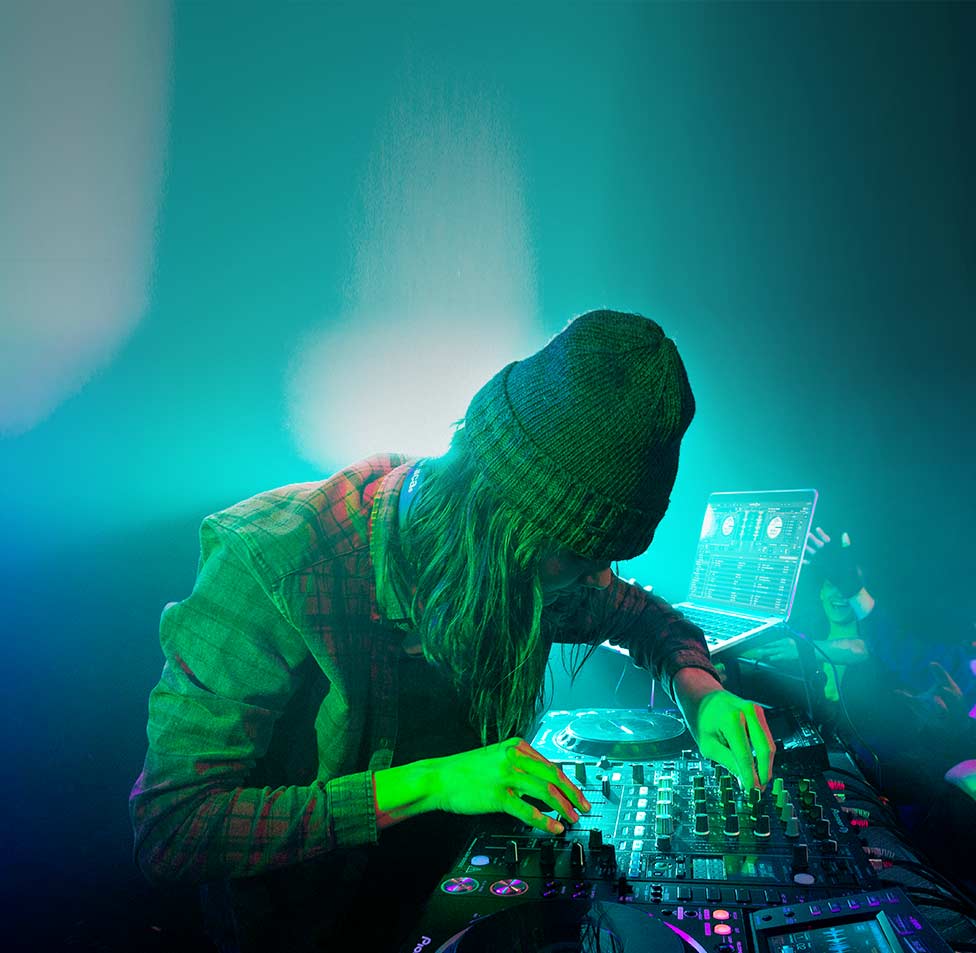 DJ in a hat turning nobs on his equipment